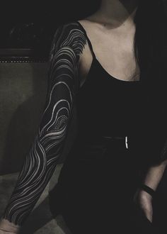 a woman with long black hair and tattoos on her arm