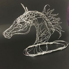 a wire sculpture of a horse's head on a black surface with purple ribbon