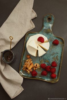 cheese, nuts and raspberries on a blue plate