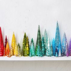 a row of colorful christmas trees sitting on top of a white shelf