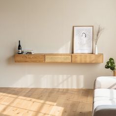 a white couch sitting next to a wooden shelf on top of a hard wood floor