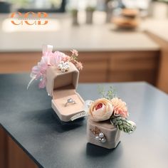 an open ring box sitting on top of a counter next to a bouquet of flowers