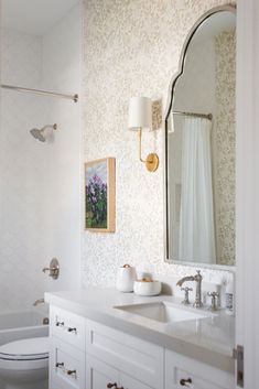 a bathroom with a white toilet sitting next to a bath tub under a large mirror