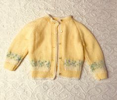 Knitted yellow long sleeve sweater. Blue and white design on bottom of sleeve and sweater. Pearl button front closure. Fitted Long Sleeve Cream Sweater, Yellow Soft Knit Sweater For Spring, Spring Yellow Soft Knit Sweater, Yellow Knitted Crew Neck Sweater, Hand Knitted Long Sleeve Spring Sweater, Hand Knitted Long Sleeve Sweater For Spring, Spring Hand Knitted Long Sleeve Sweater, Yellow Knitted Long Sleeve Sweater, Yellow Long Sleeve Knitted Sweater