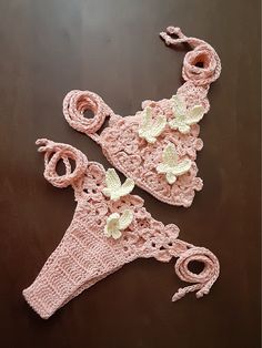 two pink crocheted hats and scarfs sitting on top of a wooden table