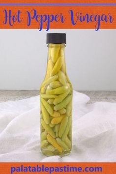 a bottle filled with green beans sitting on top of a white table