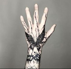 a person's hand with black and white tattoos on it holding up their palm