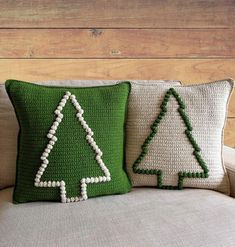 two knitted christmas trees sitting on top of a couch