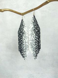 These long beaded earrings are inspired by the black, white and silver patters. Handcrafted with meticulous attention to detail, they exude timeless sophistication. Perfect for adding a touch of celestial charm to any ensemble, these earrings are sure to become a cherished addition to your jewelry collection. Dimensions: - Length: 13 cm (5 inches) - Width: 3 cm (1.2 inches) White Beaded Fringe Earrings For Festival, White Long Drop Jewelry With Beaded Fringe, White Elegant Chandelier Earrings For Festivals, White Bohemian Beaded Earrings With Black Beads, Bohemian White Earrings With Black Beads, White Beaded Fringe Long Drop Earrings, White Long Drop Beaded Fringe Earrings, White Silver Beaded Drop Earrings, Elegant White Beaded Earrings For Festivals