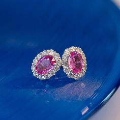 3.60 Oval Cut Pink Sapphire & Diamond Earrings in 18K White Gold.  Fall head over heels in love with these 3.60 carat pink sapphire and diamond stud earrings! Finished in 18k white gold, these studs feature two (2) 1.80 carat pink sapphires with a medium-dark, fuchsia hue. The sapphires are haloed by twenty-four (24) .06 carat Round Brilliant cut diamonds. The diamonds are bright and borderline colorless, lending an exquisite contrast of color to the pink sapphires. These stud earrings are a rom Sapphire Diamond Earrings, Pink Diamond Earrings, Pink Sapphire Jewelry, Head Over Heels In Love, Pink Sapphire Earrings, Sapphire And Diamond Earrings, Sapphire Studs, Big Diamond, Head Over Heels