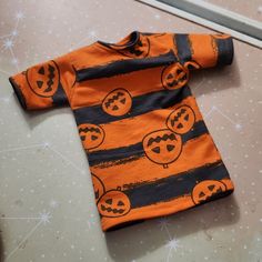 an orange and black striped shirt with jack - o'- lantern faces on it