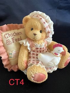 a small teddy bear sitting on top of a table next to a sign that says chicken feed