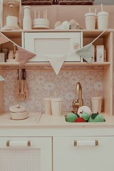 a kitchen with white cabinets and pink wallpaper