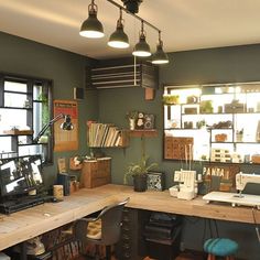 a home office with lots of desk space and hanging lights above the desk, along with several bookshelves