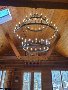 a chandelier hanging from the ceiling in a room with wood paneling and windows