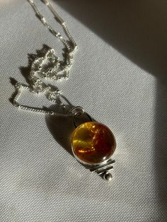 An amber sterling silver necklace typically symbolizes a blend of elegance and natural beauty. Amber, fossilized tree resin, is often associated with healing, protection, and energy.  When set in sterling silver, a durable and beautiful metal, it enhances the natural glow of amber while adding a touch of sophistication.  This combination can represent a balance between the earth's organic beauty and human craftsmanship, often symbolizing timelessness and a connection to nature. Baltic Amber Gemstone Necklaces, Amber Sterling Silver Necklaces With Cabochon, Amber Cabochon Necklaces In Sterling Silver, Amber Cabochon Necklace In Sterling Silver, Amber Sterling Silver Necklace With Cabochon, Amber Citrine Round Pendant Jewelry, Minimalist Amber Sterling Silver Jewelry, Minimalist Sterling Silver Amber Jewelry, Spiritual Citrine Amber Necklace