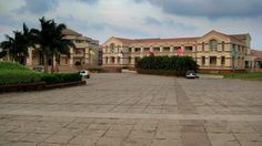 an empty parking lot in front of a large building with palm trees and flags on it