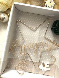 a white box with some gold wire in it and decorations on the table next to it