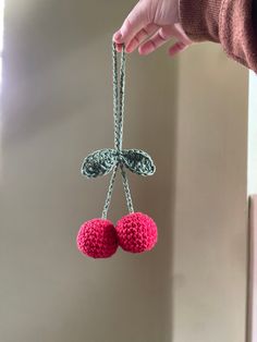 a person is holding two crocheted balls in the air with chains attached to them