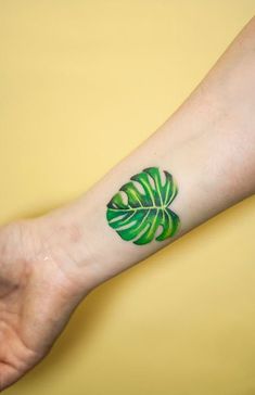 a green leaf tattoo on the left arm