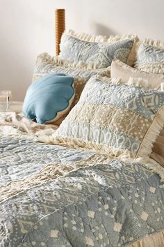 a bed with blue and white comforter, pillows and pillow on top of it