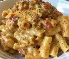 a white plate topped with pasta covered in sauce and meats on top of it