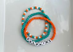 These Dolphins bracelets are the perfect way to show your team pride for the big game! Pair them with any outfit. This listing is for 3 bracelets as shown in pictures.  TO ORDER:  1. Pick bracelet length  2. Pick letter color 3. Submit and I'll get to work :)  PRODUCT DETAILS:  - Bracelets are made with sturdy jewelry elastic - Listing is for three bracelets  - All orders are final. Please double check your bracelet size  CARING TIPS:  - Do not expose jewelry to water  - Treat and store jewelry gently  - Roll bracelets on rather than stretching band to get on  Don't see your teams bracelets on our shop? Or have a custom team bracelet you want? Head to this link to order your custom ones!  https://kanaeohana.etsy.com/listing/1591607617/custom-sports-team-bracelets-team  We are HAPPY to do b Sporty Beaded Bracelets With Letter Beads For Team Events, Team Spirit Bracelets With Letter Beads, Team Spirit Wristband With Letter Beads For Game Day, Team Spirit Letter Beads Wristband For Game Day, Game Day Bracelets With Letter And Round Beads, Team Spirit Beaded Bracelets For Game Day, Multicolor Beaded Bracelets For Game Day, Miami Dolphins Bracelets, Multicolor Team Spirit Beaded Bracelets For Game Day