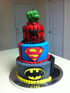 the cake is made to look like batman and spiderman's hands are on top