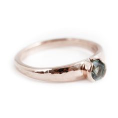 a rose gold ring with a blue diamond