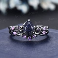 an elegant ring with purple stones and leaves on the side, sitting on top of a book