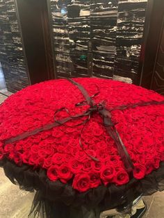 a large red rose covered round box with black ribbon