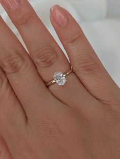 a woman's hand with a diamond ring on top of her finger and the other hand holding an engagement ring