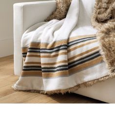 a white couch with a striped blanket on top of it next to a wooden floor