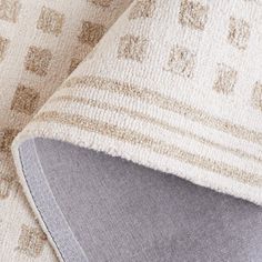 a close up view of the corner of a cushion on a couch with an area rug underneath it