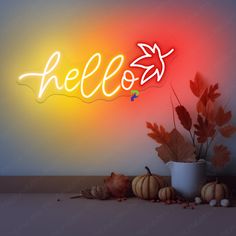 a neon sign that says hello with autumn leaves and acorns on the floor