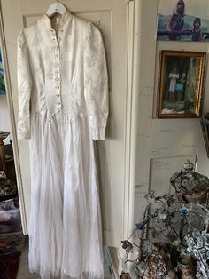 a white dress hanging on a wall in a room with pictures and other items around it