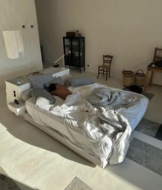 a person laying on top of a bed in a room with white walls and flooring