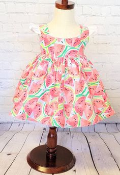 "Display dress is a size 18/24 month on a 2t mannequin. Dress is shown with a tulle petticoat underneath which is NOT INCLUDED in the purchase of dress. It is for display purposes only.  This watermelon dress features bright watermelons on a light blue background and has a full skirt, shoulder straps and ties at the waist. It would be so fun to wear to a picnic, a \"One in a Melon\" birthday or event.  Bodices are lined with soft white cotton and the back closes with Kam snaps for easy on and of Cute Summer Dresses For Dress-up Occasions, Cute A-line Sundress For Garden Party, Cute Green A-line Dress, Summer Sleeveless Dress For Dress-up, Summer Sleeveless Playtime Dresses, Summer Sleeveless Dresses For Playtime, Sweet Summer Beach Dresses, Playful Summer Dresses For Playtime, Sweet Sleeveless Dresses For Playtime