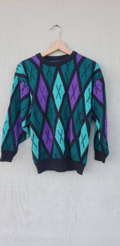 "Loving this rad sweater featuring a diamond green & purple colorblock design,  relaxed fit! Looks suuuper cute paired with leggings & your fave kicks! Great Vintage condition. Vintage circa 1990. Details: * Great Vintage condition * Vintage circa 90s  * Soft Fabric (unsure of fabric)  * Length from front: 22\" * Length from back: 24\" * Bust: 19\" * Sleeve from Shoulder: 18\"" Retro Purple Sweater For Winter, 90s Style Purple Sweater For Fall, 90s Style Purple Fall Sweater, Retro Purple Winter Sweater, 90s Purple Winter Sweater, 90s Green Winter Sweater, Green 90s Style Winter Sweater, Green 90s Winter Sweater, Purple Fits