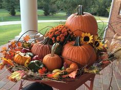 a wheelbarrow filled with pumpkins and gourds sitting on a porch