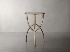 a round table with gold metal legs and a marble top on a gray floor in front of a white wall