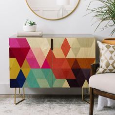 a sideboard with colorful geometric designs on it and a potted plant next to it