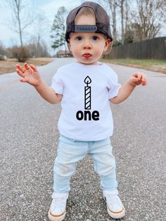 Hey there, Party-Ready Parents! 🎉 This 1st Birthday shirt is going to be the highlight of the big day, like a shiny disco ball at a toddler dance-off. But, hold on to your confetti cannons and check out our size guide before clicking that 'add to cart' button. We want your little one to rock this tee with style and ease. And guess what? If you're aiming for that oh-so-comfy, perfect fit, just stick to their usual size - it's as easy as building a block tower! THE LOWDOWN 🎈 Our hero here is the Playful Party Tops With Letter Print, Funny First Birthday T-shirt With Letter Print, First Birthday T-shirt With Text Print, Black T-shirt With Custom Print For First Birthday, Playful Short Sleeve T-shirt For First Birthday, Casual T-shirt With Funny Print For First Birthday, Toddler Dance, 1st Birthday Shirts, Boys Graphic Tee