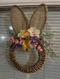 a wreath with flowers and bunny ears hanging on the wall