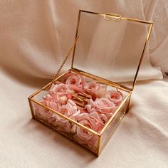 an open box with pink flowers inside on a white cloth covered tableclothed surface