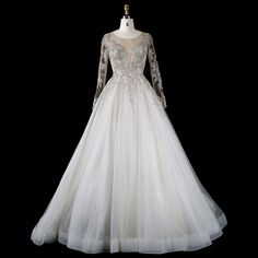 a white wedding dress with long sleeves on a mannequin head stand in front of a black background