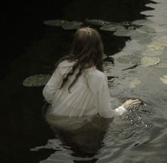 a woman is sitting in the water with her hands on her hip and looking at something