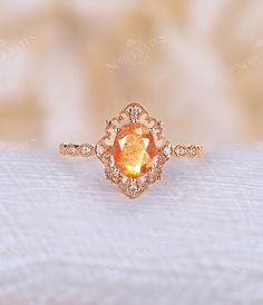 an orange diamond ring sitting on top of a white cloth