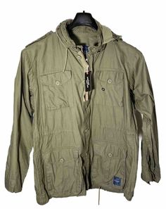 Get ready to conquer the outdoors with this Military Jacket from ROAKE. Made from durable cotton, this mid-length coat features a full zip and button closure, hideaway hood, and multiple pockets for all your essentials. The solid green color and army/outdoor theme make it perfect for summer, fall, or spring walks. Suitable for travel, casual wear, or work, this regular-fit jacket is designed to provide both comfort and style. It comes in size L and has accents of buttons and zippers that add to its overall charm. So gear up and step out in style with this ROAKE Men's Cotton Fatigue Utility Jacket, now with tags!