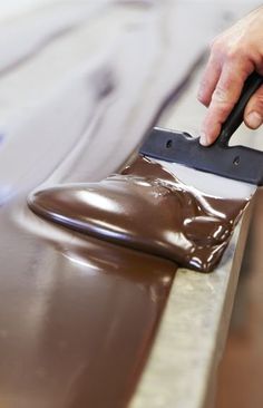 a person using a knife to paint a piece of chocolate